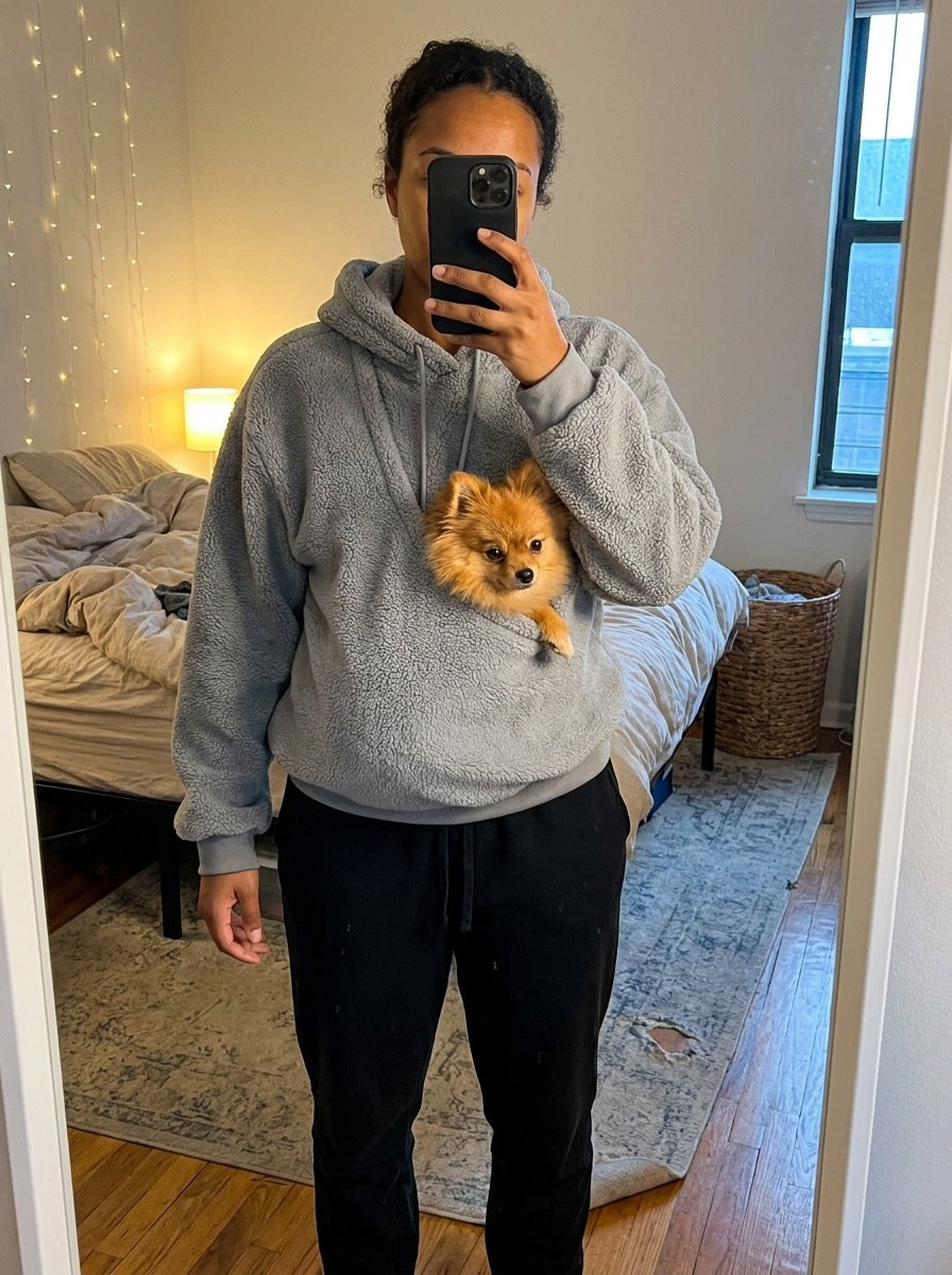 Mirror selfie: a woman in a grey JOEY pouch hoodie with a small orange Pomeranian riding in the front pouch.